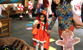 Girl dressed as Little Red Riding Hood and her mother walk through Candy Land event