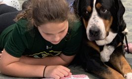 Girl reading book to a therapy dog