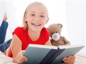 Girl holding book and looking up at camera smiling