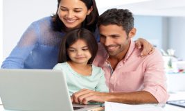 Family - wife, husband, and daughter - looking at their laptop