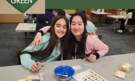 Two teen girls smiling with arms around each other, volunteering to package seeds. Text says "Live Green" inside a green heart. "Community service for junior high & high school students."